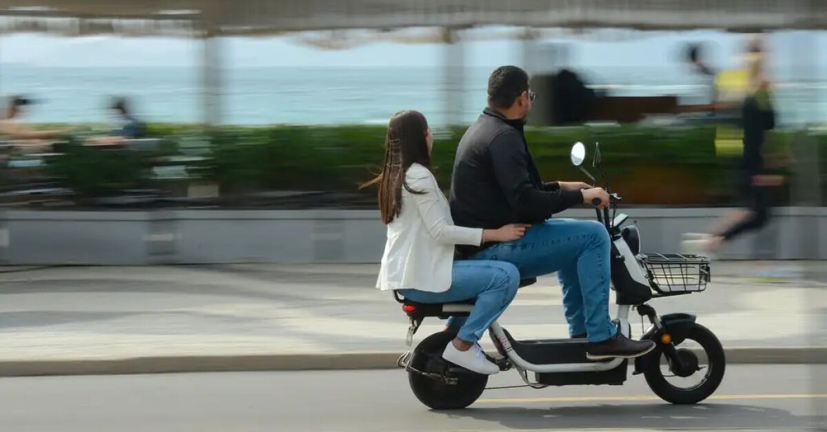Motociclista e passageira sem capacete.