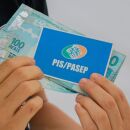 Pessoa com cart&atilde;o do PIS/Pasep e dinheiro do abono.