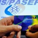 Pessoas segurando cart&atilde;o da Caixa Econ&ocirc;mica e imagem do PIS/Pasep de fundo.