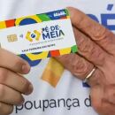 Pessoa segurando cart&atilde;o do P&eacute;-de-Meia ao lado da m&atilde;o de Lula.