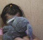 Crian&ccedil;a com medo, segurando bicho de pel&uacute;cia.