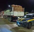 Carro da PRF ao lado de carreta, em via.