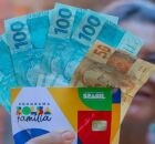 Senhora segurando cart&atilde;o do Bolsa Fam&iacute;lia e dinheiro do benef&iacute;cio.
