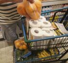 Pessoa colocando compras em carrinho de supermercado.