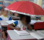 Crian&ccedil;a na escola com guarda chuva.