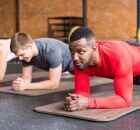 Pessoas em academia fazendo exerc&iacute;cio de prancha.