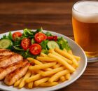 Prato de comida ao lado de um copo de cerveja.