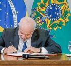 Lula assinando papel. 