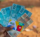 Pessoa segurando dinheiro e cart&atilde;o do Bolsa Fam&iacute;lia.