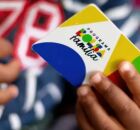 Crian&ccedil;a segurando cart&atilde;o do Bolsa Fam&iacute;lia. 