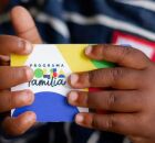 Crian&ccedil;a segurando cart&atilde;o do Bolsa Fam&iacute;lia.