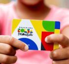 Crian&ccedil;a segurando cart&atilde;o do Bolsa Fam&iacute;lia.