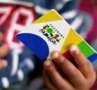 Crian&ccedil;a seguran&ccedil;a segurando cart&atilde;o do Bolsa Fam&iacute;lia.