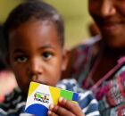 Crian&ccedil;a segurando cart&atilde;o do Bolsa Fam&iacute;lia ao lado da m&atilde;e.