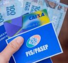 Pessoa segurando cart&atilde;o do PIS/Pasep, da Caixa e dinheiro do benef&iacute;cio.