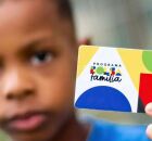 Crian&ccedil;a segurando cart&atilde;o do Bolsa Fam&iacute;lia.