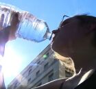 Mulher bebendo &aacute;gua devido ao calor.