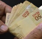 Pessoa com notas de R$ 50,00 na m&atilde;o.