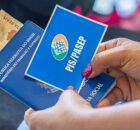 Mulher com cart&atilde;o do PIS/Pasep e dinheiro do benef&iacute;cio.