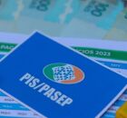 Cart&atilde;o do PIS/Pasep ao lado de dinheiro do abono e calculadoras.