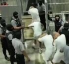 Detentos sendo conduzidos &agrave;s celas por policiais.