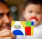 M&atilde;e com beb&ecirc; segurando cart&atilde;o do Bolsa Fam&iacute;lia.