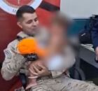 Pol&iacute;cial com crian&ccedil;a no bra&ccedil;o.