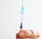 Pessoa com seringa de vacina contra HPV em m&atilde;os.