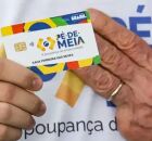 Pessoa segurando cart&atilde;o do P&eacute;-de-Meia ao lado da m&atilde;o de Lula.