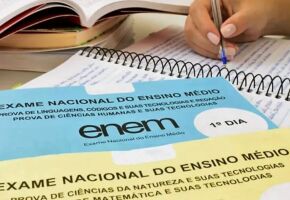 Pessoa estudando com caderno do Enem de lado.