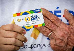 M&atilde;o do presidente Lula e pessoa segurando cart&atilde;o do P&eacute;-de-Meia.
