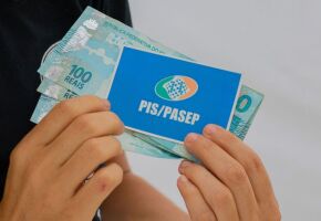 Pessoa com cart&atilde;o do PIS/Pasep e dinheiro do abono.