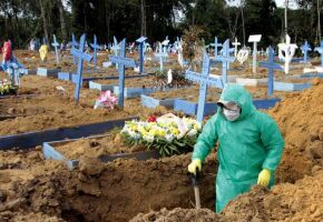 Coveiro com roupa de prote&ccedil;&atilde;o em cemit&eacute;rio, durante per&iacute;odo de pandemia, no Brasil.