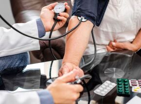 Profissional de sa&uacute;de acompanha a press&atilde;o arterial de um paciente para refor&ccedil;ar a preven&ccedil;&atilde;o do AVC.