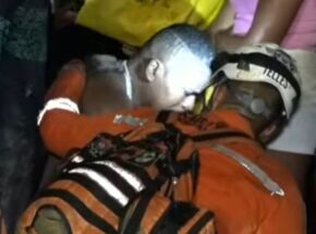 Esposo e pai das v&iacute;timas sendo consolado por um bombeiro.