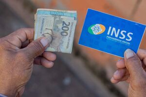 Pessoa idosa segurando cart&atilde;o e benef&iacute;cio do INSS.