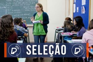 Professora ensinando alunos em sala de aula. 