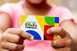 Crian&ccedil;a segurando cart&atilde;o do Bolsa Fam&iacute;lia.