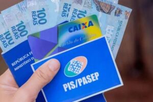 Pessoa segurando cart&atilde;o do PIS/Pasep, da Caixa e dinheiro do benef&iacute;cio.