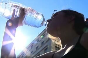 Mulher bebendo &aacute;gua devido ao calor.