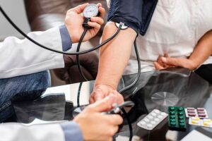 Profissional de sa&uacute;de acompanha a press&atilde;o arterial de um paciente para refor&ccedil;ar a preven&ccedil;&atilde;o do AVC.