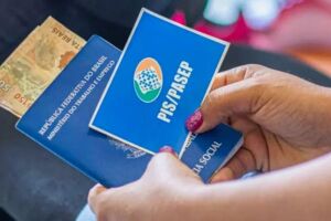 Mulher com cart&atilde;o do PIS/Pasep e dinheiro do benef&iacute;cio.