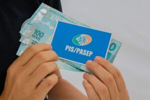 Pessoa com cart&atilde;o do PIS/Pasep e dinheiro do abono.