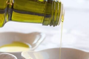 Garrafa com azeite de oliva sendo derramado.