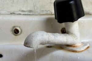 Torneira aberta vazando &aacute;gua.