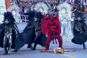 Desfile de escola de samba representando o Diabo e Jesus.