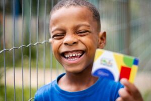 Crian&ccedil;a segurando cart&atilde;o do Bolsa Fam&iacute;lia.