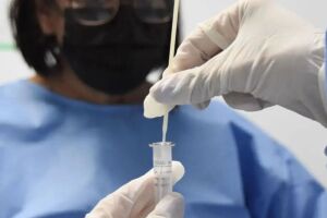 Cientistas com frasco para analisar Covid-19.