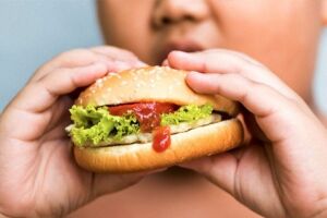Crian&ccedil;a comendo hamburguer.