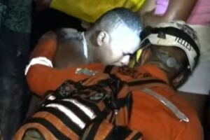 Esposo e pai das v&iacute;timas sendo consolado por um bombeiro.